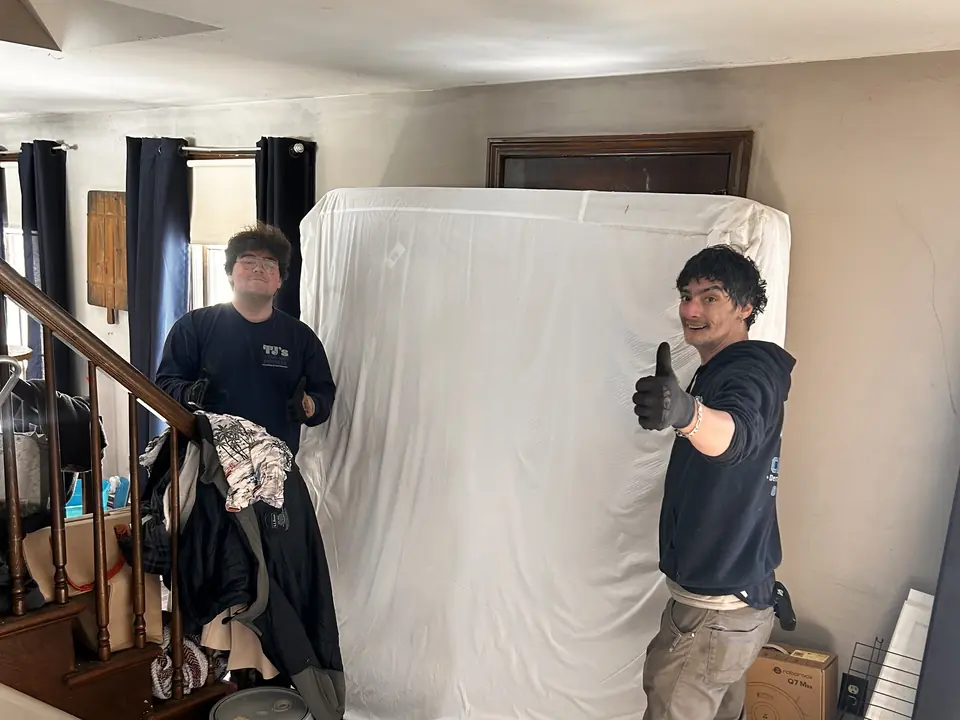 Two TJ's crew members carrying out a mattress